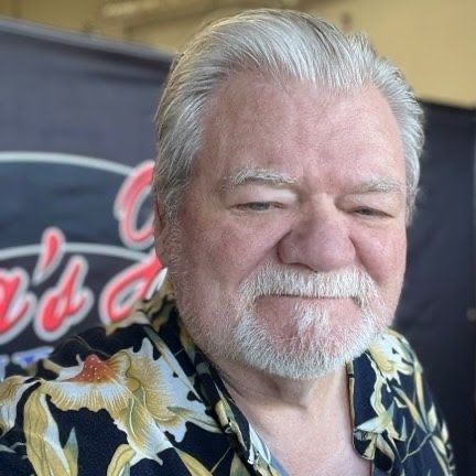 A man with a beard is wearing a floral shirt