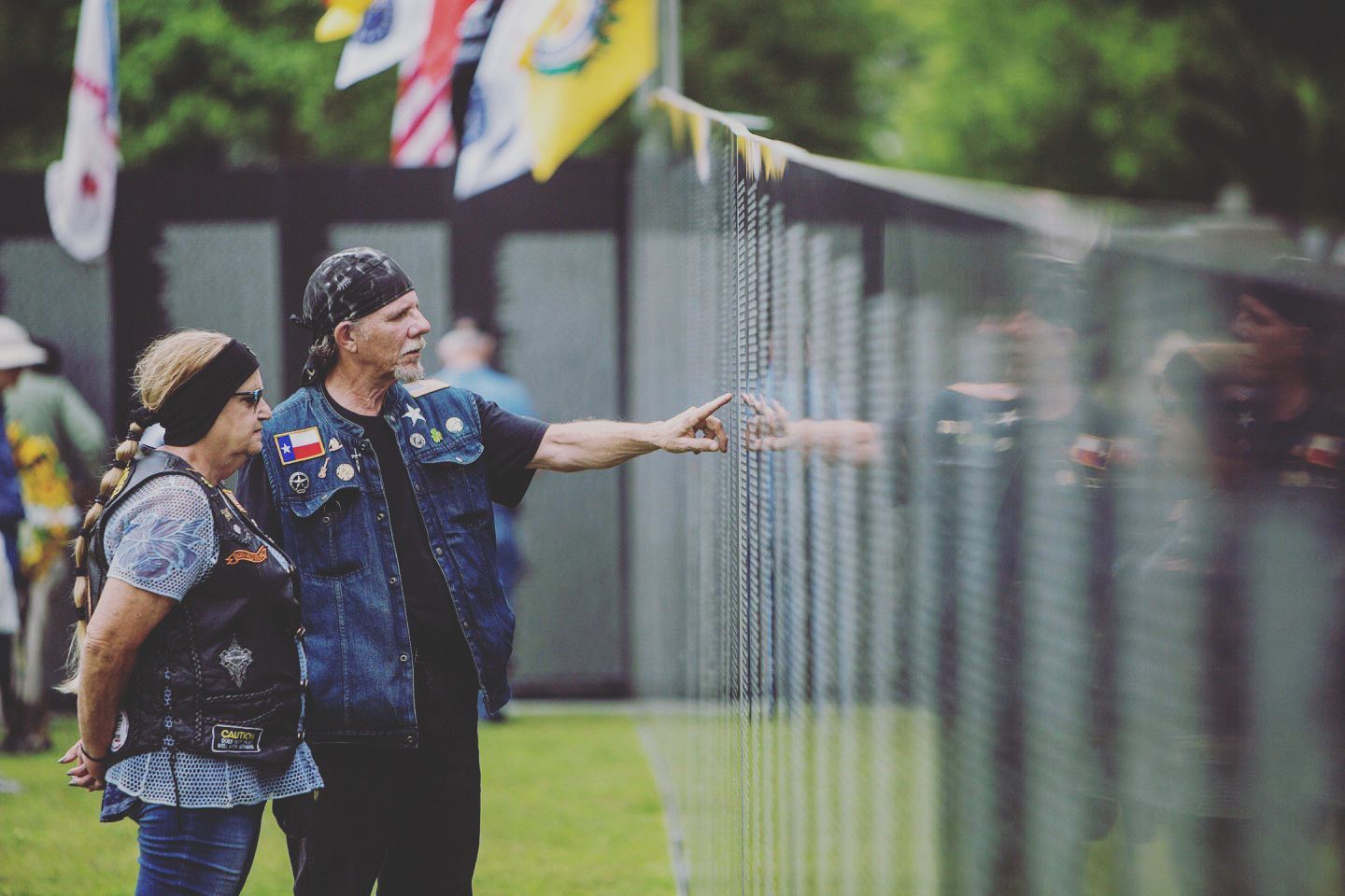 A man and a woman are standing next to each other in front of a fence.