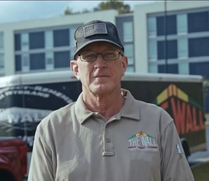 A man wearing a hat and a shirt that says the wall