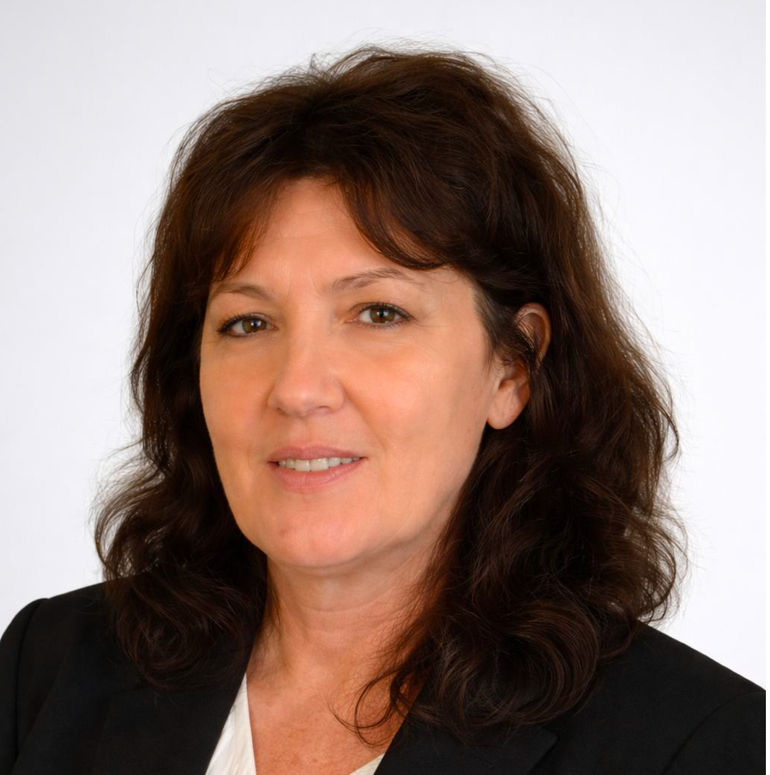 A woman wearing a black top and a white sweater is smiling for the camera.