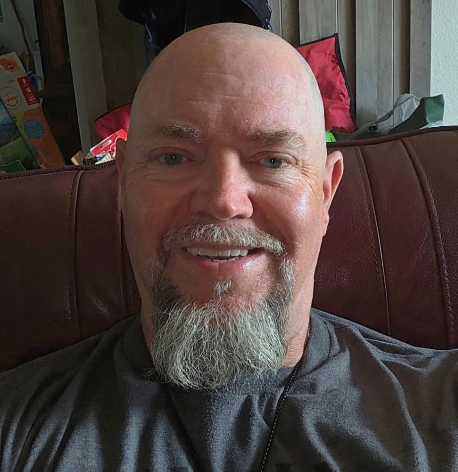 A woman wearing a black top and a white sweater is smiling for the camera.