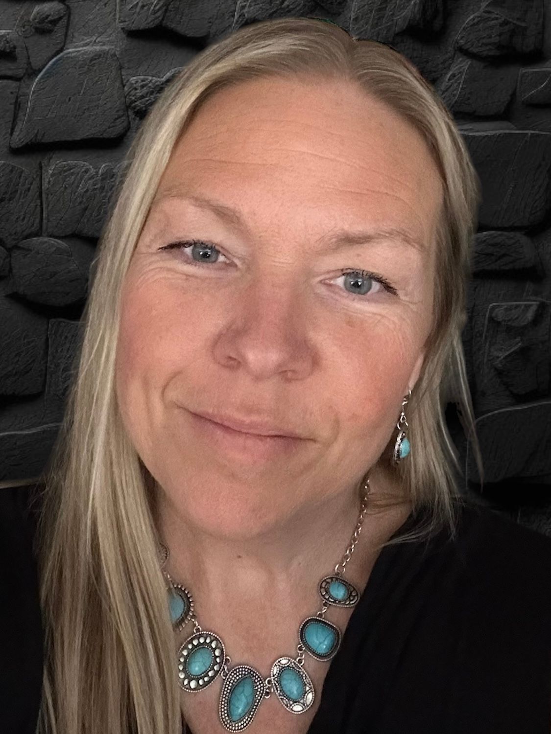 A woman is smiling in front of an american tribe banner