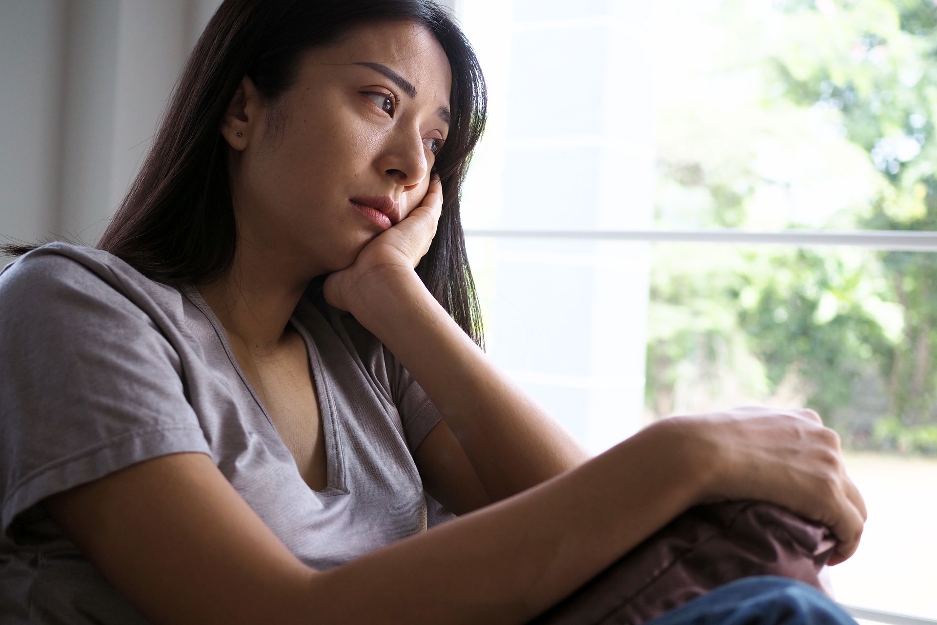 an asian woman staring sadly out the window