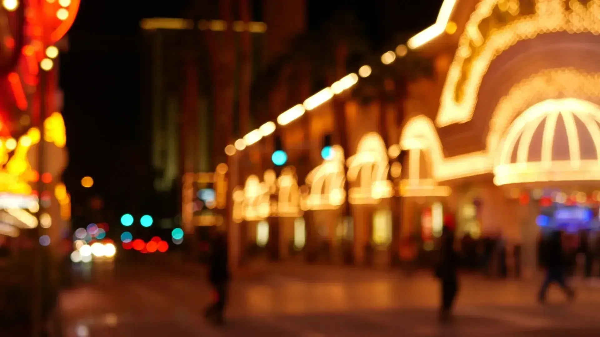 A blurry picture of a city street at night with a casino in the background.