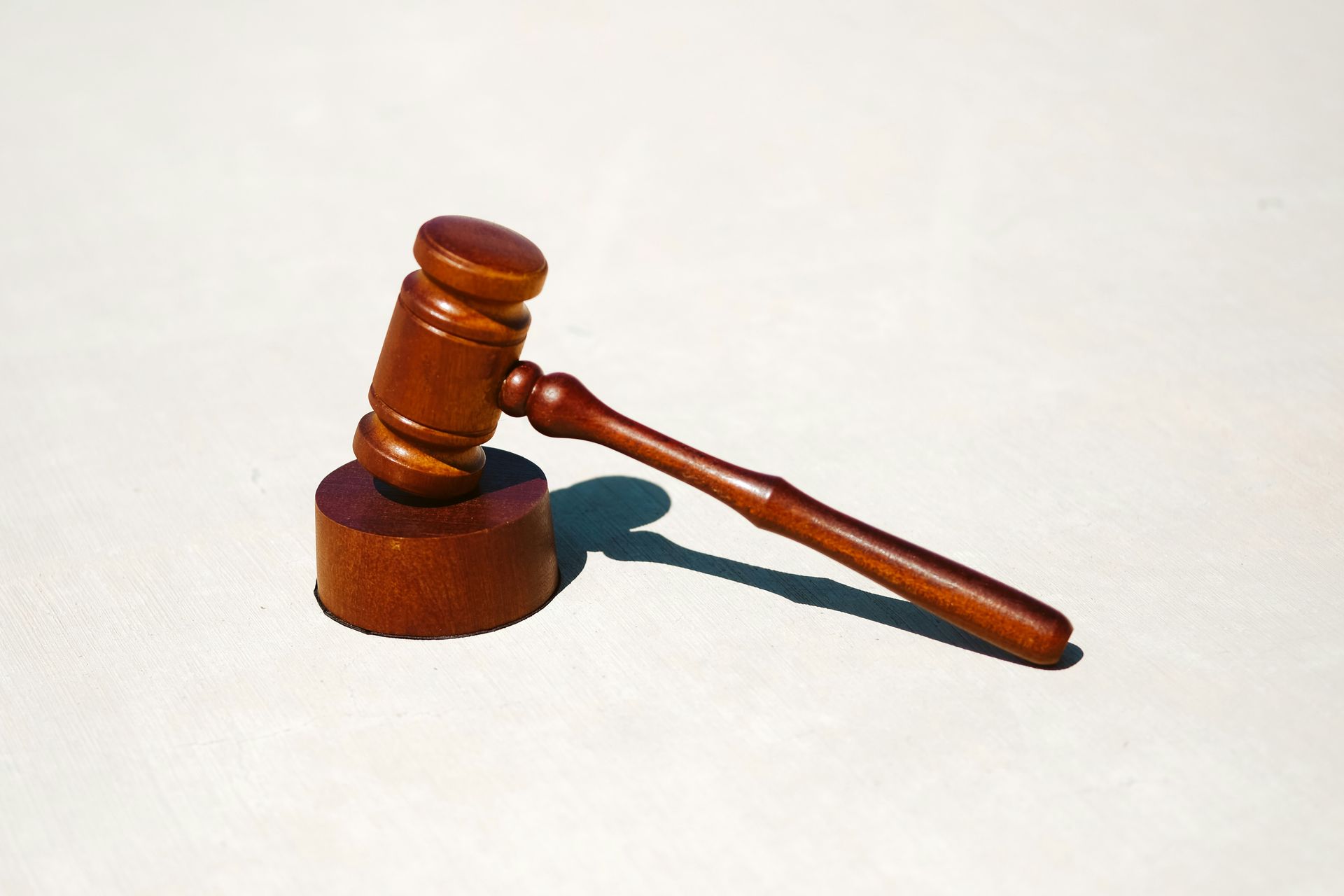 Wooden judge’s gavel resting on a circular sound block, symbolizing law and legal authority.