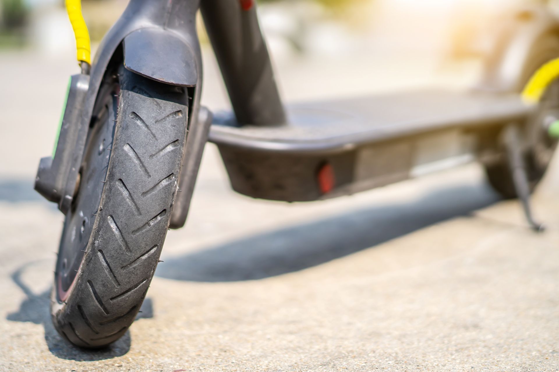 Close-up of an electric scooter wheel and deck on a city street.