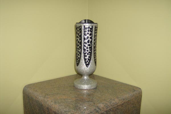 A silver vase is sitting on top of a marble block.