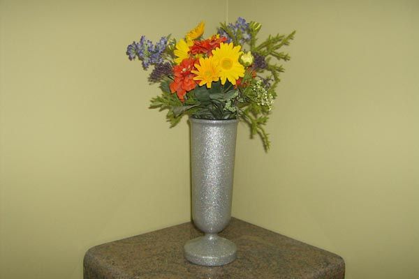 A silver vase filled with flowers is sitting on a table.