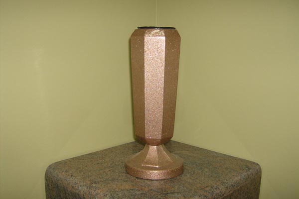 A copper vase is sitting on top of a stone pedestal.