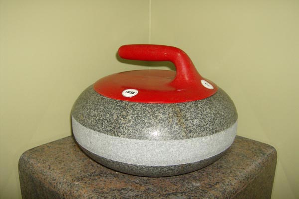 A curling stone with a red handle is sitting on a table.