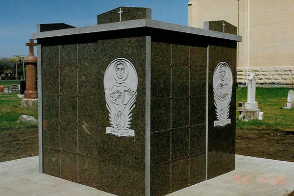 A cubicle in a cemetery with a cross on top of it