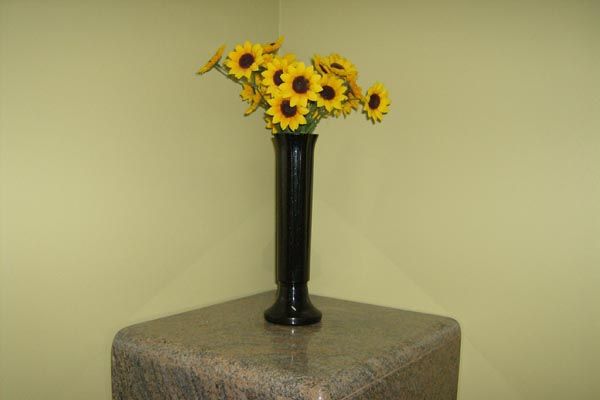 A black vase filled with yellow flowers on a table
