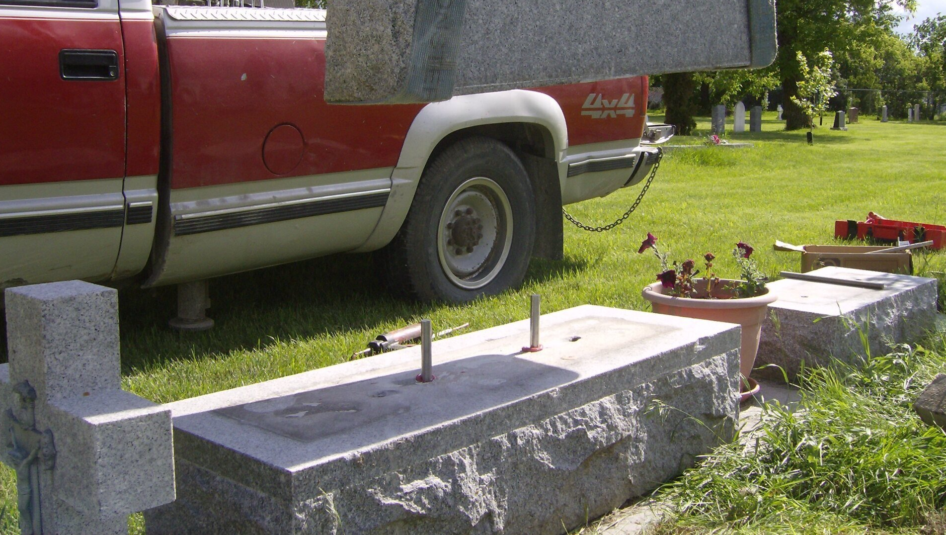 A red chevy truck is parked next to a grave