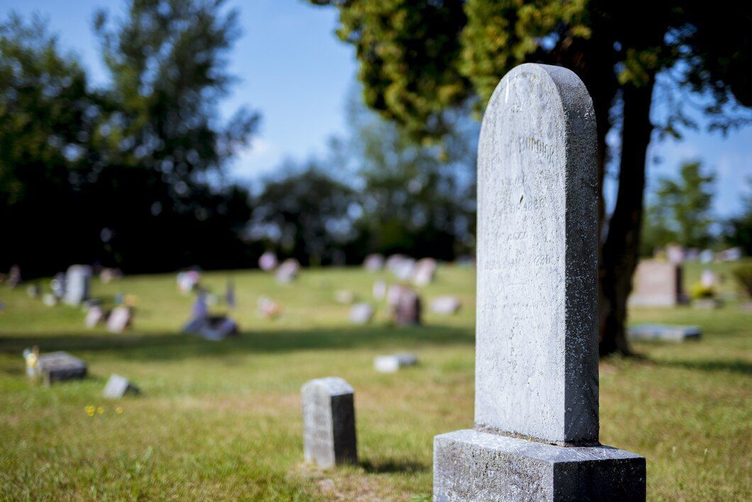 A gravestone in a cemetery with trees in the background.