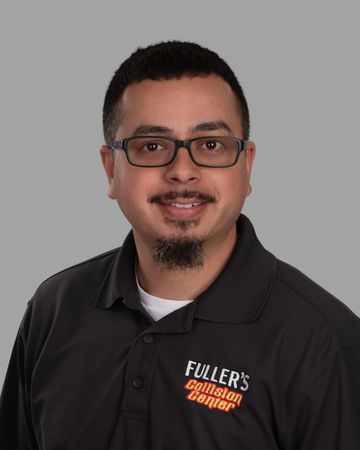 A man wearing glasses and a fuller 's collision center shirt is smiling for the camera.