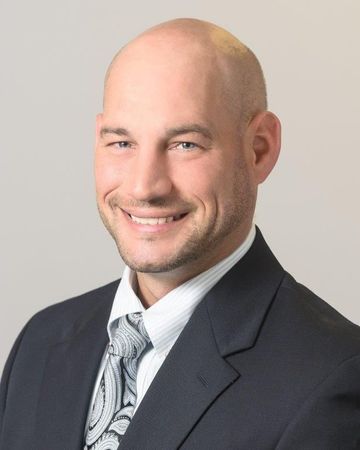 A man in a suit and tie is smiling for the camera