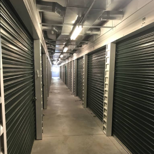 Row of tall, beige shelving units in a storage room; some units hold books.