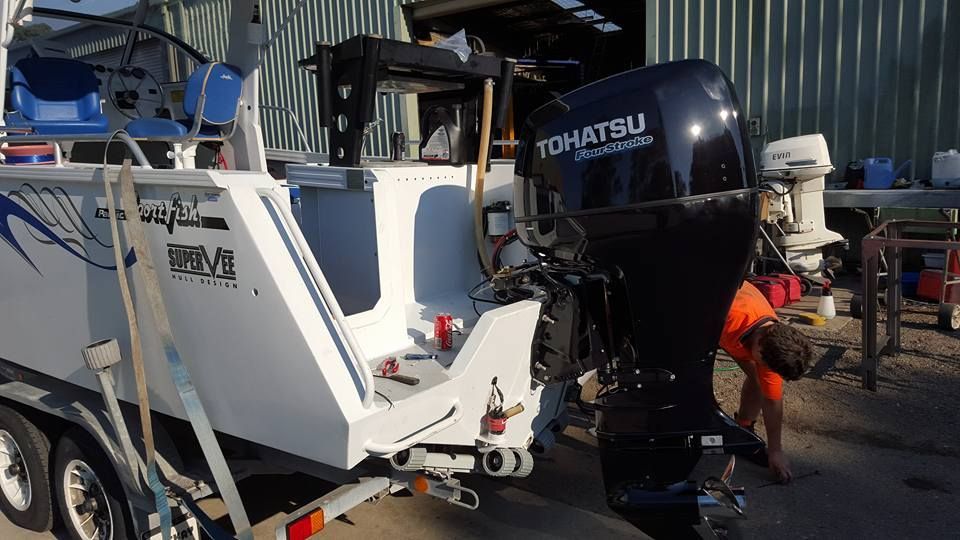 A Man Is Working On The Engine Of A Boat — Mark's Outboards & More In Muswellbrook, NSW