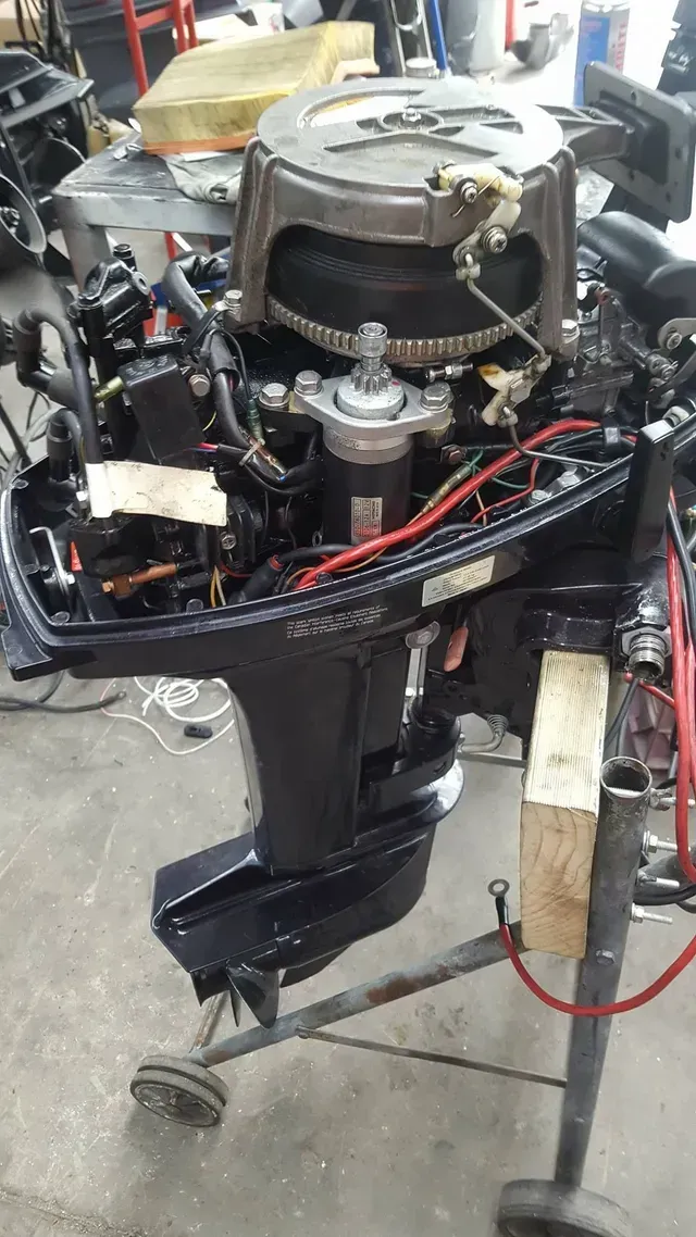 A Boat Engine Is Sitting On A Cart In A Garage — Mark's Outboards & More In Muswellbrook, NSW