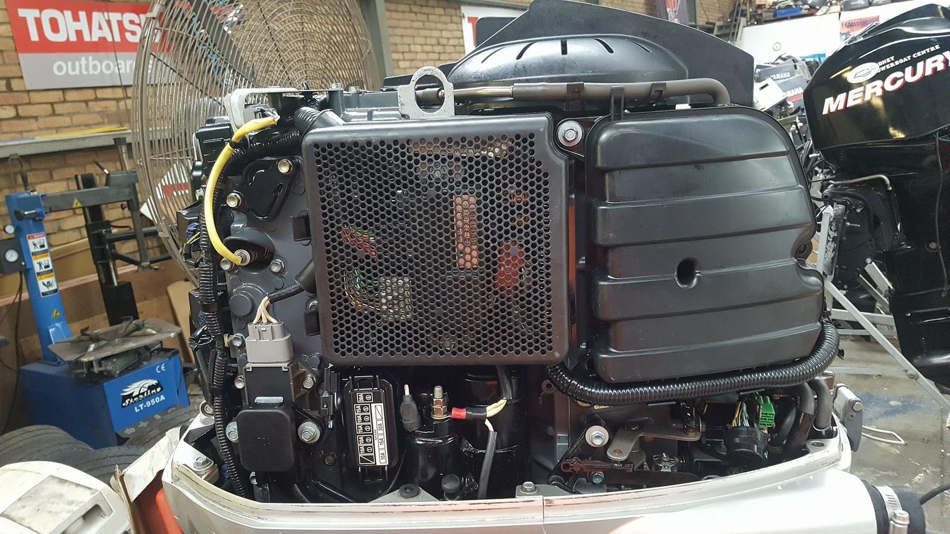 A Boat Engine Is Sitting On Top Of A Boat In A Garage — Mark's Outboards & More In Central Coast, NSW