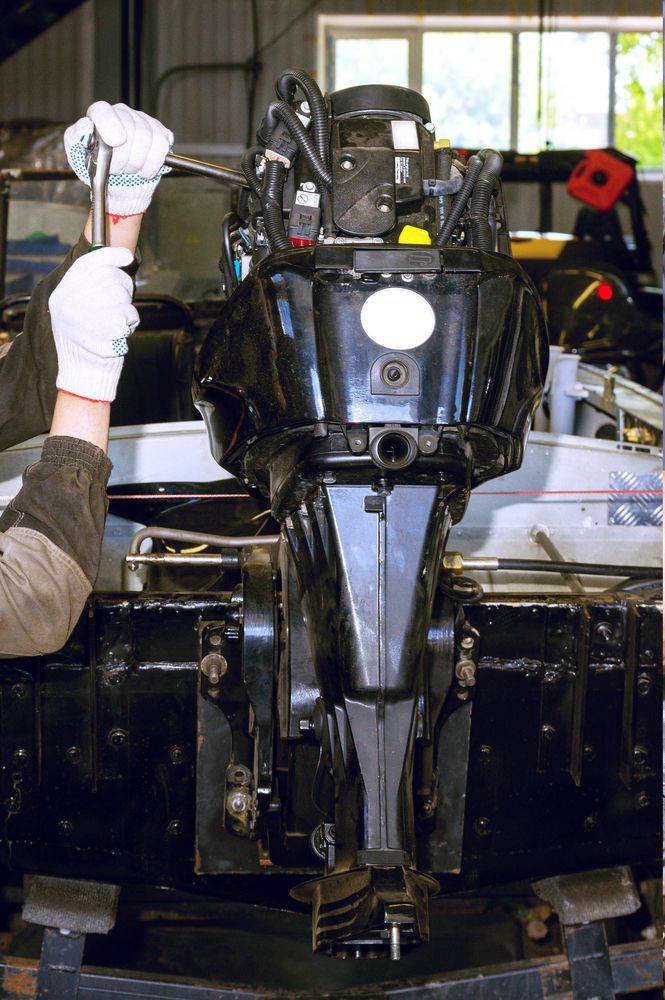 A Person Is Working On A Boat Engine In A Garage — Mark's Outboards & More In Kurri Kurri, NSW