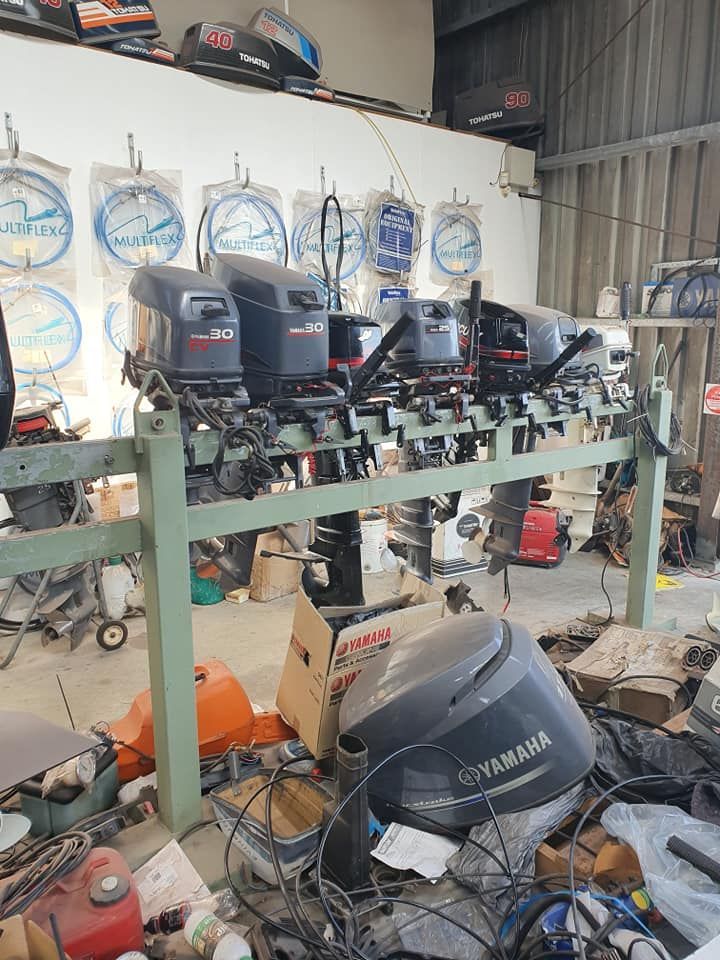 A Bunch Of Outboard Motors Are Sitting On A Rack In A Garage — Mark's Outboards & More In Central Coast, NSW