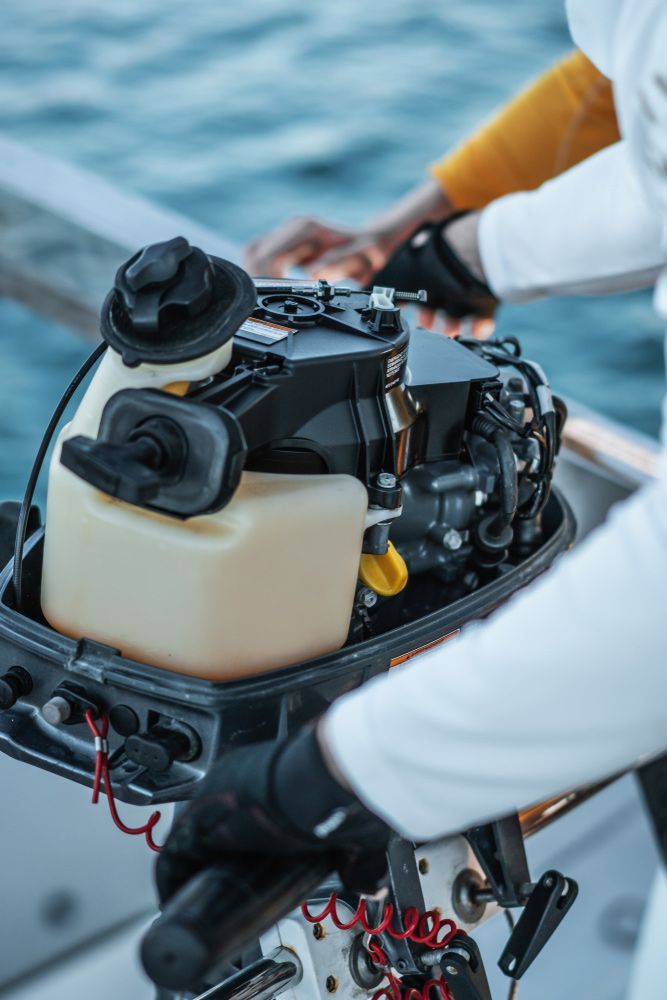 A Person Is Holding An Outboard Motor On A Boat — Mark's Outboards & More In Newcastle, NSW