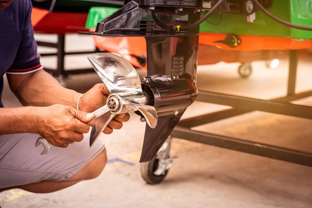 A Man Is Fixing The Propeller Of A Boat With A Wrench — Mark's Outboards & More In Newcastle, NSW