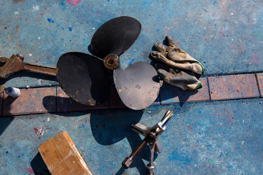 A Propeller Is Laying On The Ground Next To A Pair Of Gloves — Mark's Outboards & More In Cessnock, NSW