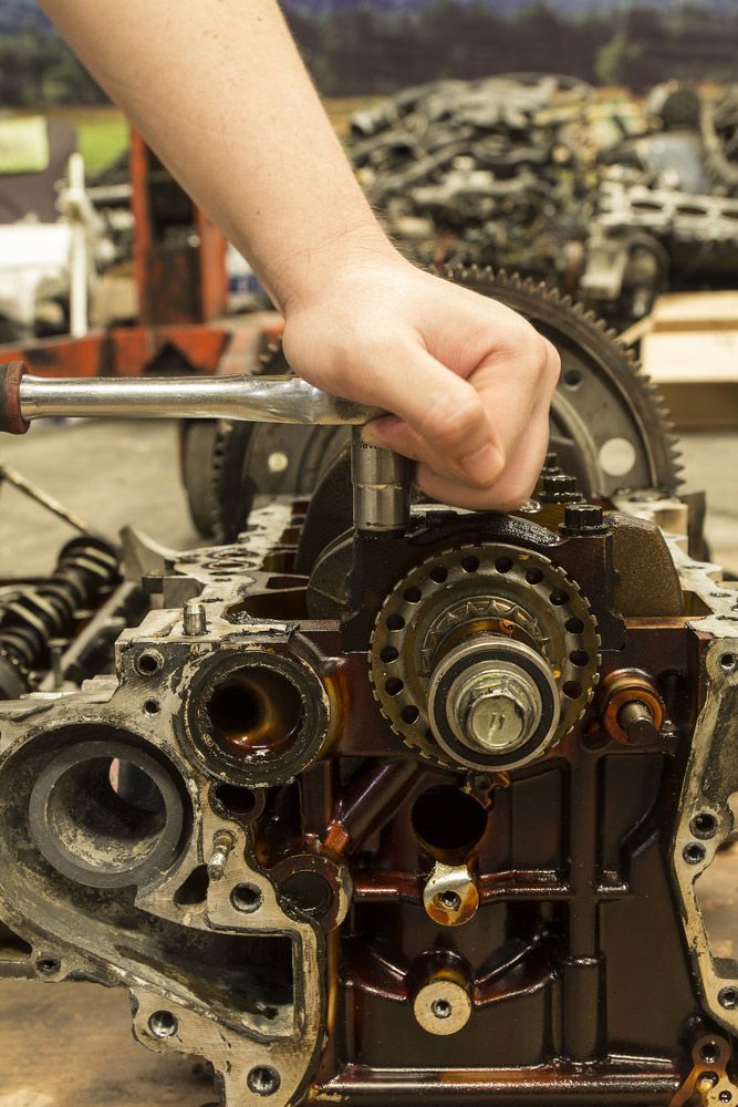 A Person Is Working On A Car Engine With A Wrench — Mark's Outboards & More In Newcastle, NSW