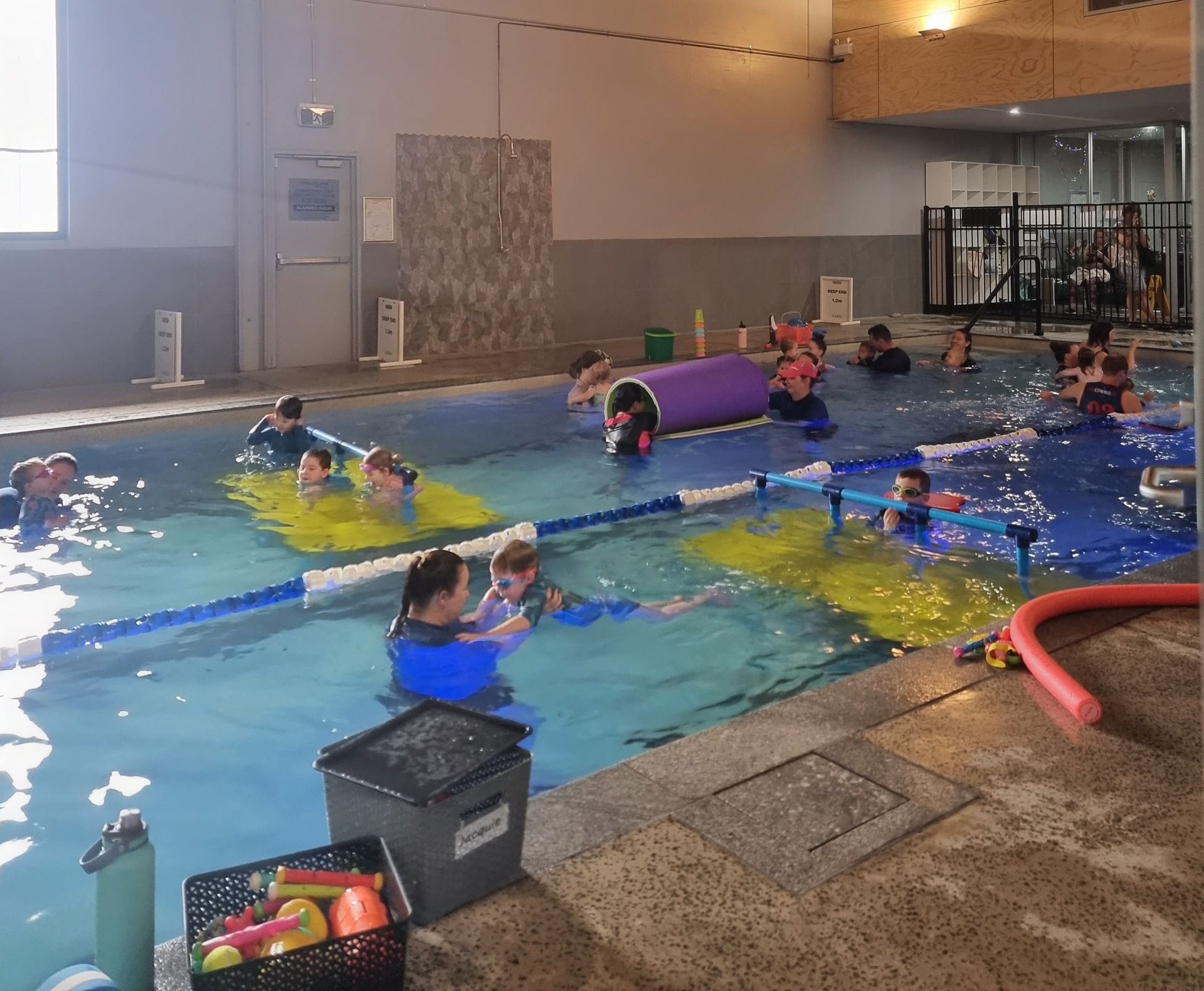 A Woman is Holding a Child in a Swimming Pool — DNA Aquatics in Bundaberg, QLD