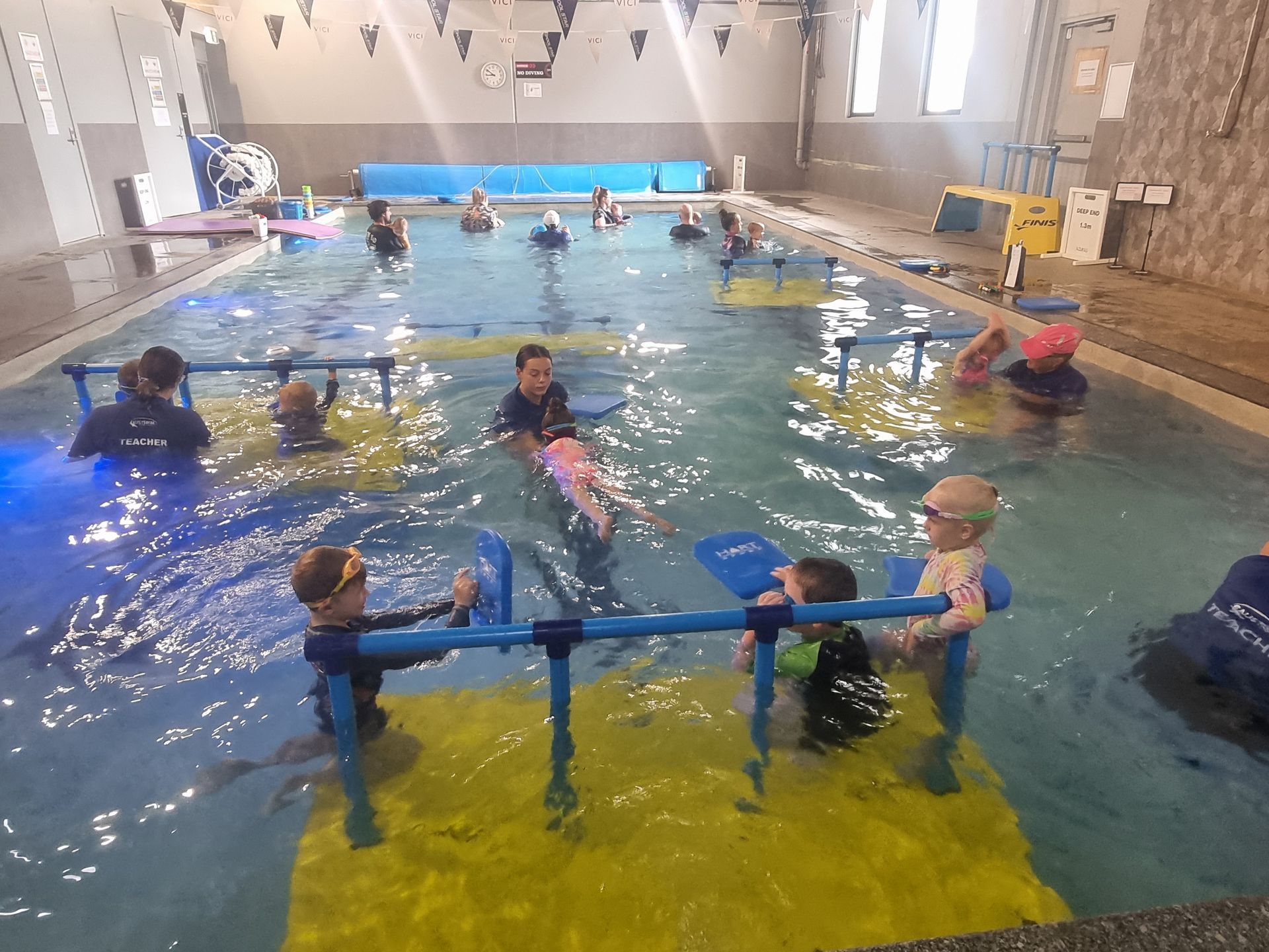 A Man is Teaching a Little Girl How to Swim in a Swimming Pool — DNA Aquatics in Bundaberg, QLD