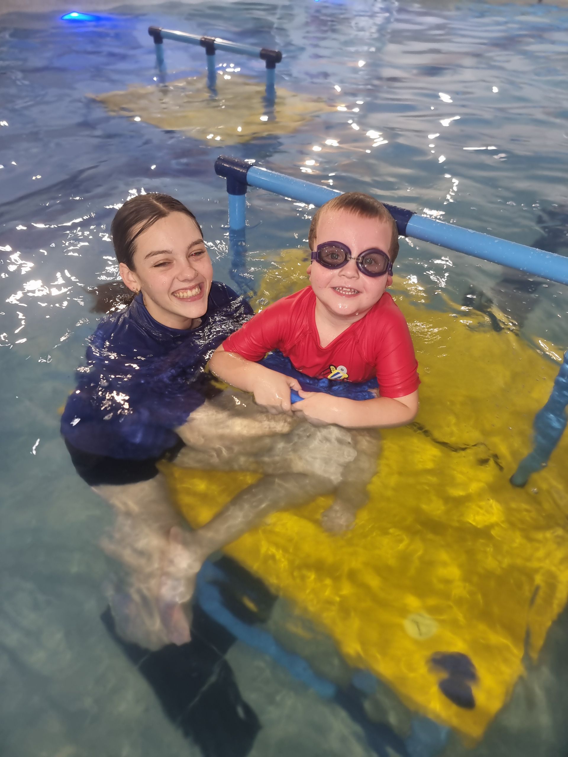 A Woman is Holding a Child in a Swimming Pool — DNA Aquatics in Bundaberg, QLD