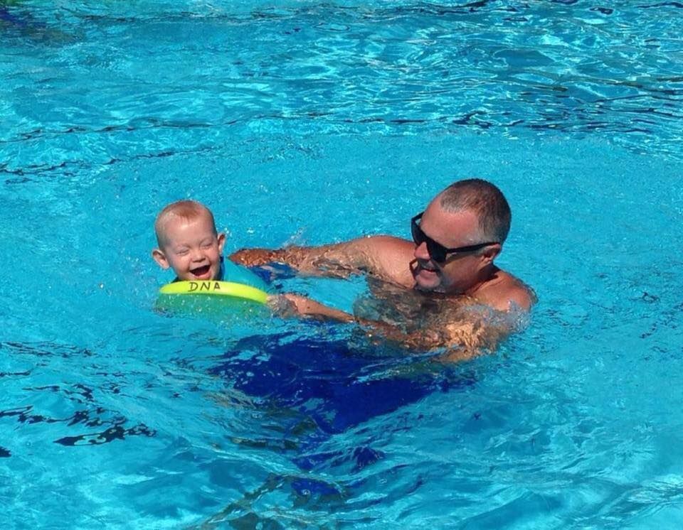 A Man is Holding a Baby in a Swimming Pool — DNA Aquatics in Bundaberg, QLD
