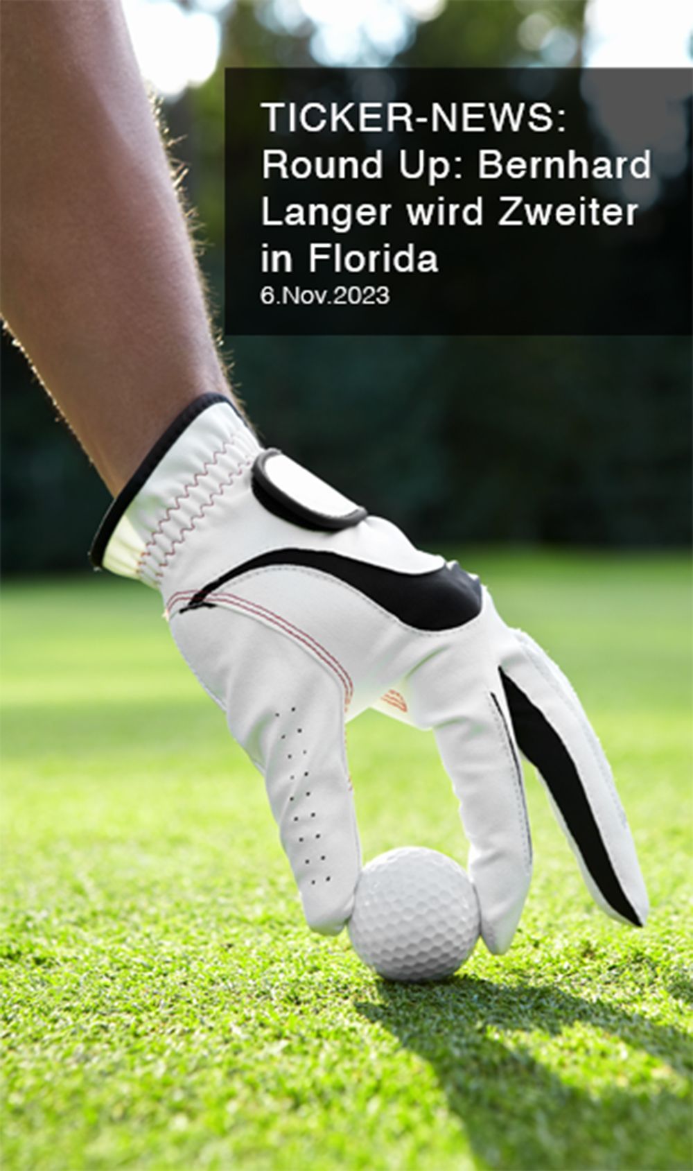 Eine Person mit einem Golfhandschuh hält auf einem Golfplatz einen Golfball.