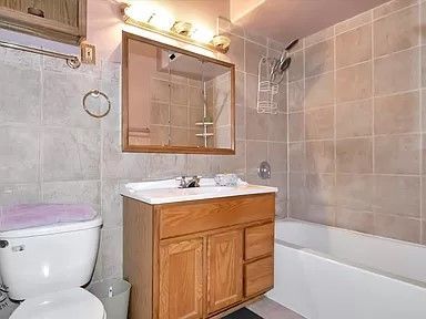 A bathroom with a toilet , sink , mirror and bathtub.