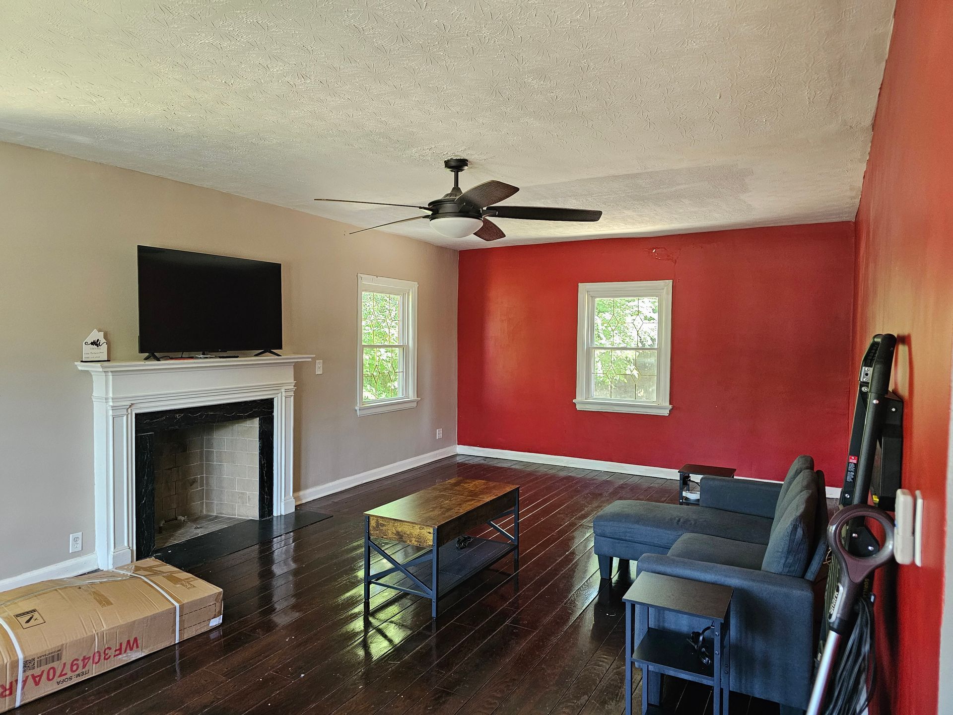 A living room with red walls and a ceiling fan
