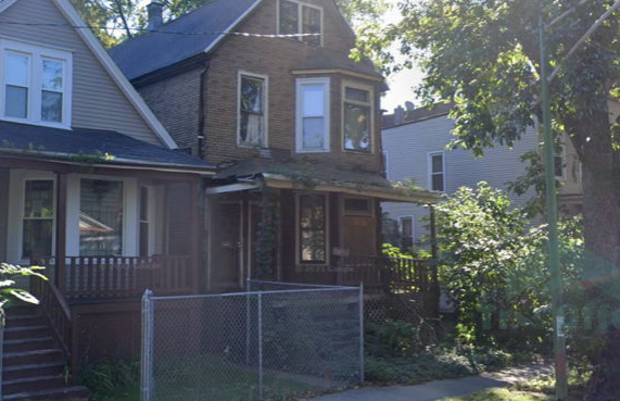A brick house with a chain link fence in front of it