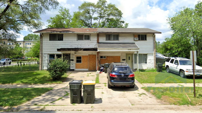 A couple of cars are parked in front of a house.