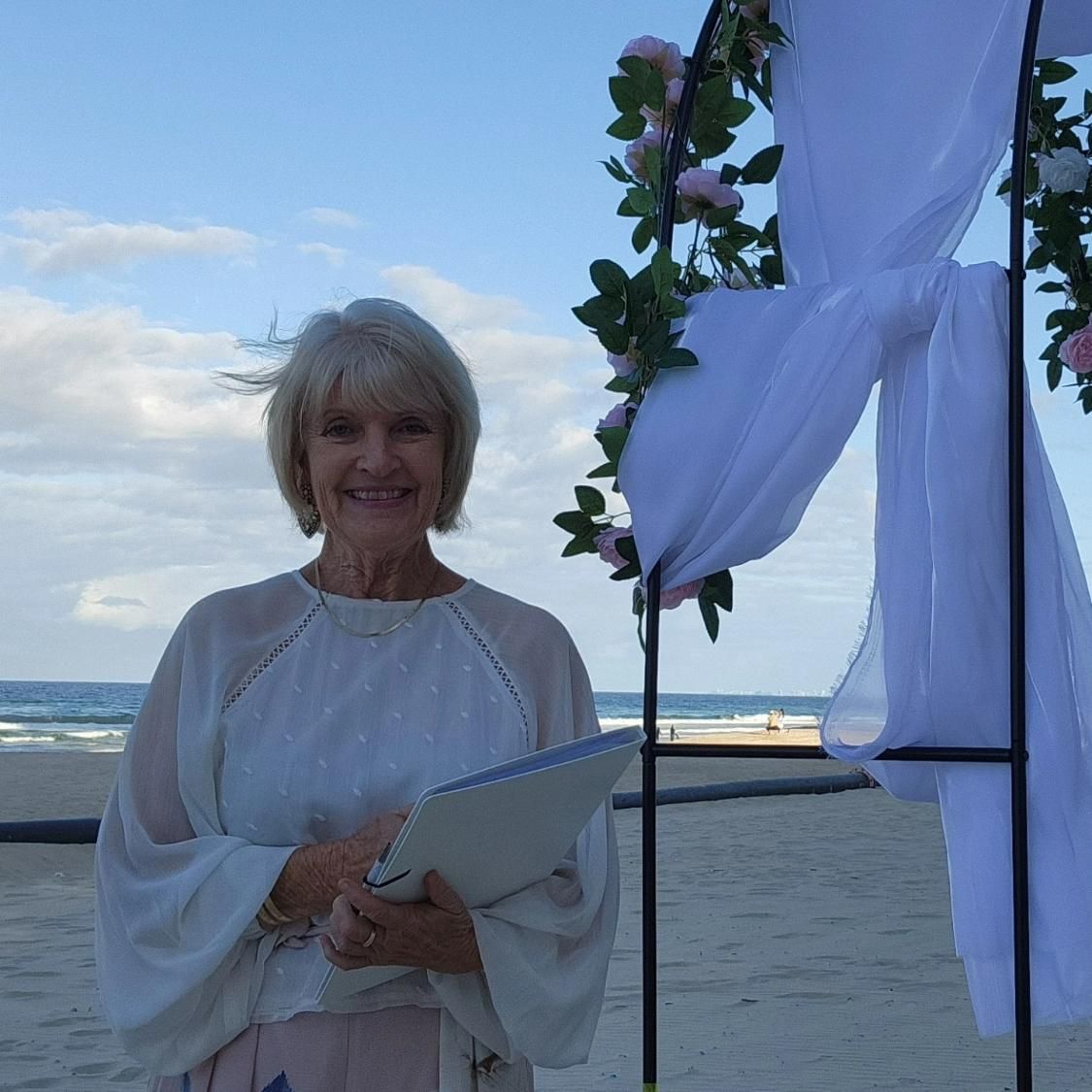 A Woman Is Standing on A Beach Holding a Clipboard — Vivienne Celebrant - Gold Coast Wedding Celebrant in Casuarina, NSW