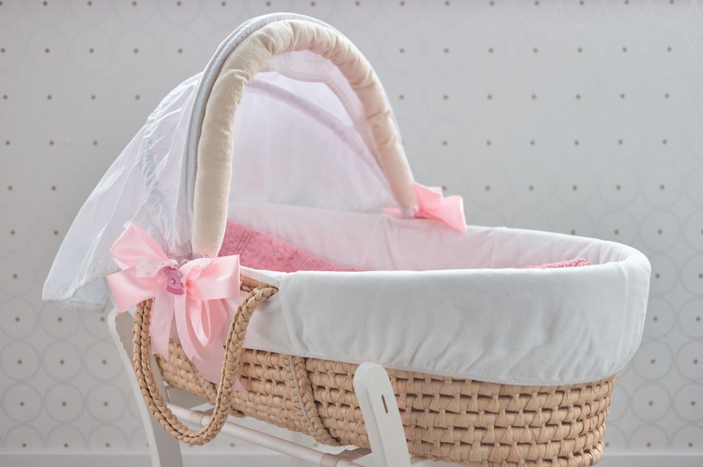 A baby bassinet with pink ribbons attached