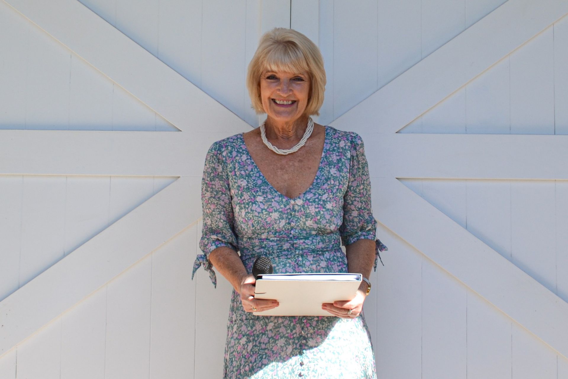 A Woman in A Dress Is Holding a Tablet and Smiling — Vivienne Celebrant - Gold Coast Wedding Celebrant in Mudgeeraba, QLD