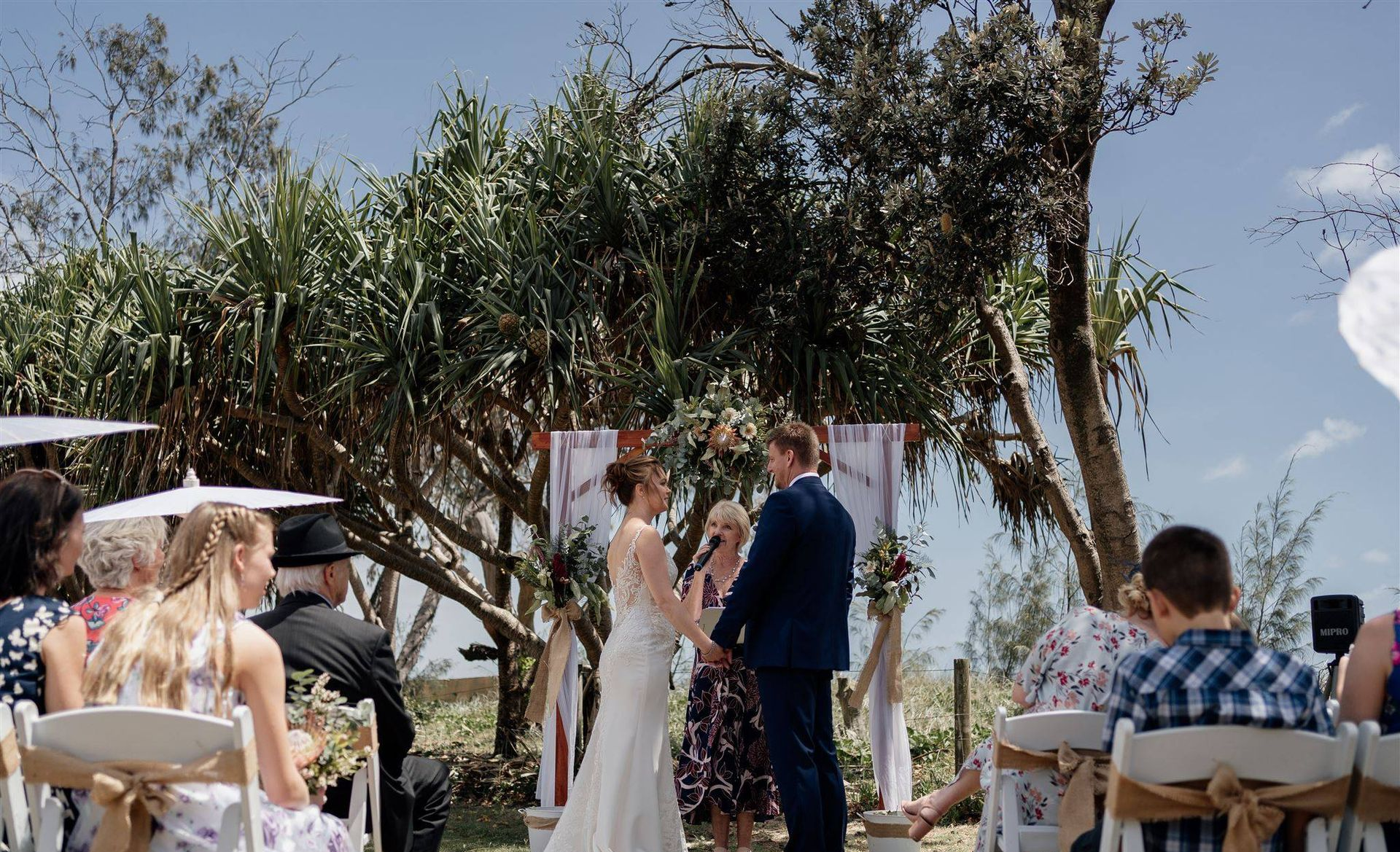 Bride and groom getting married outdoors by a wedding celebrant