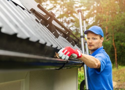 A man is cleaning a gutter on the roof of a house in Bradford.