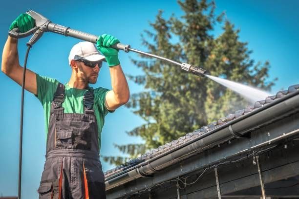 A man is cleaning the roof of a Bradford home with a soft pressure washer.