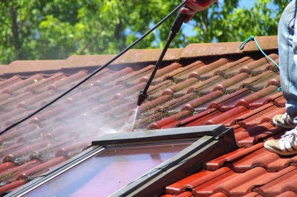 A person is cleaning a roof with a soft pressure washer in Bradford.