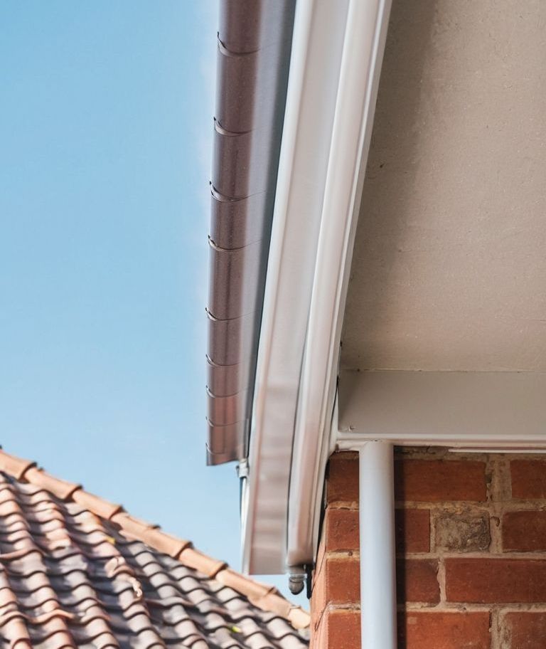 A close up of a gutter on the side of a brick building.