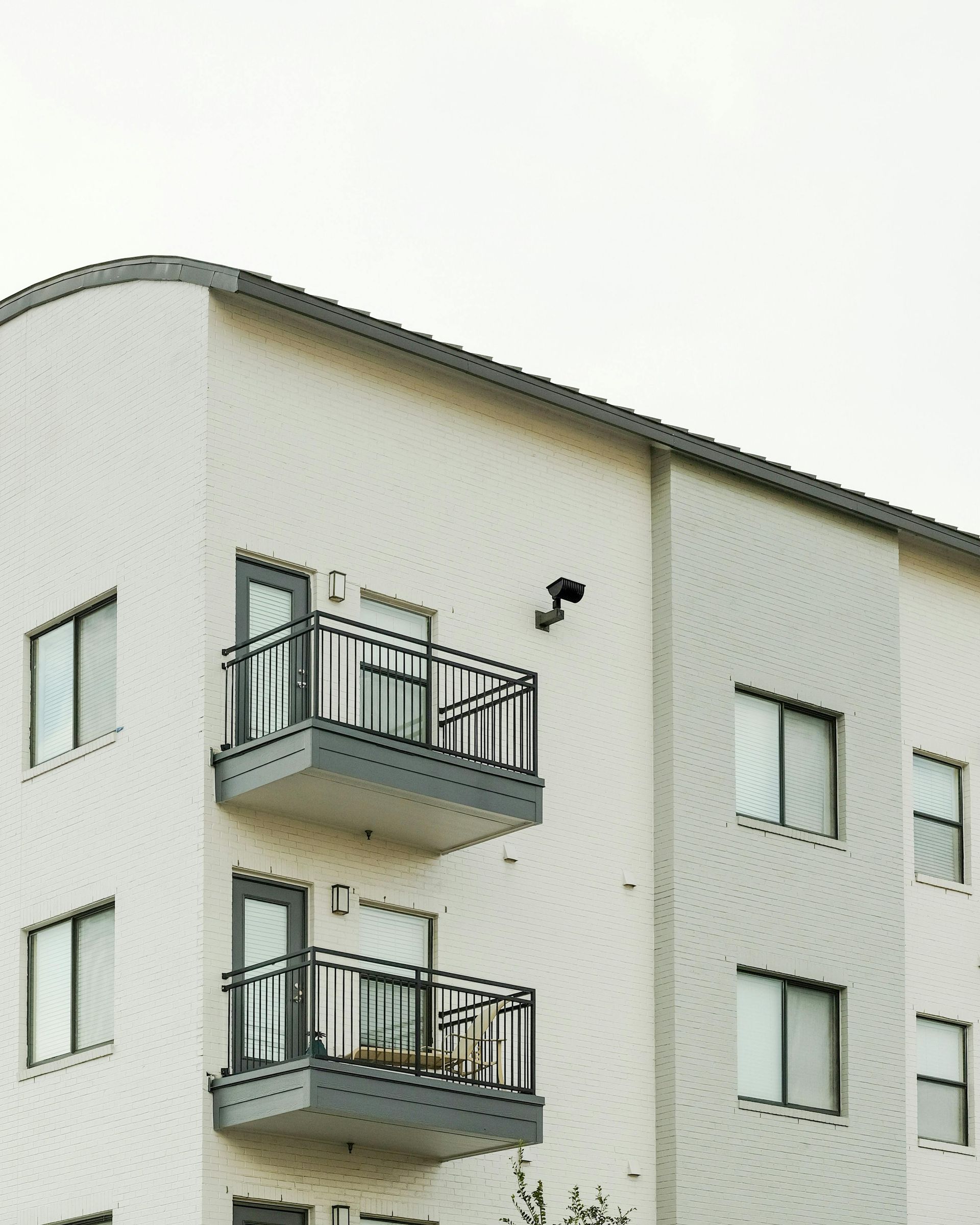 Exterior view of a multi-story apartment building with beige siding and two levels of small private balconies.