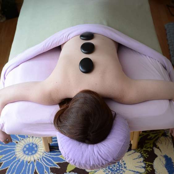 Top View Of Beautiful Young Woman Lying On Front With Spa Stones On Her Back