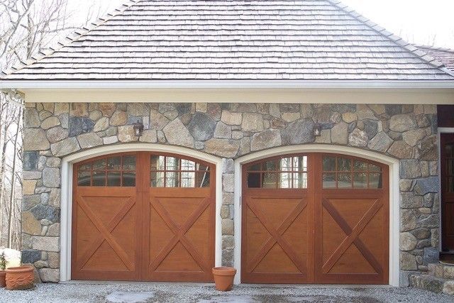 Two-car garage with light blue doors and gray roof; on a concrete driveway, surrounded by trees.